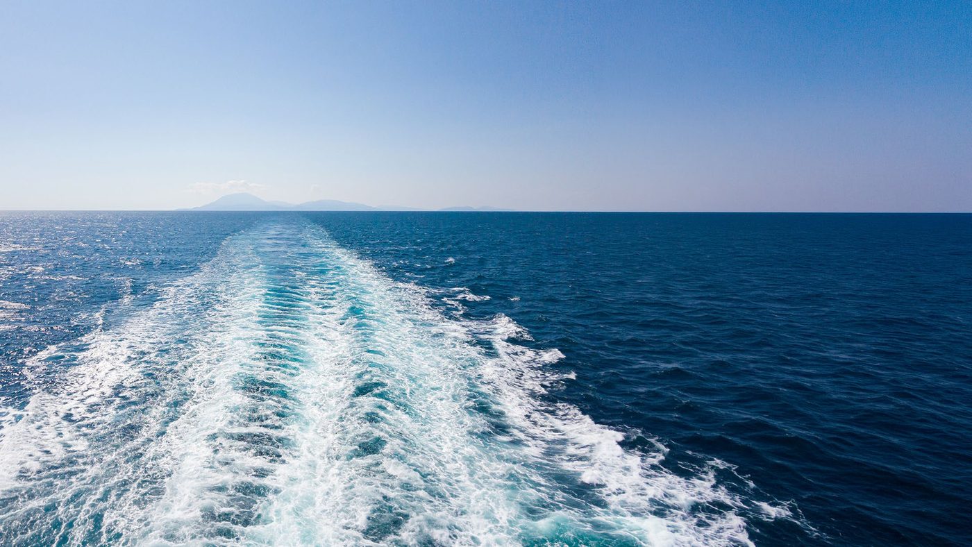 Ship's wake trailing across a calm open sea towards the horizon