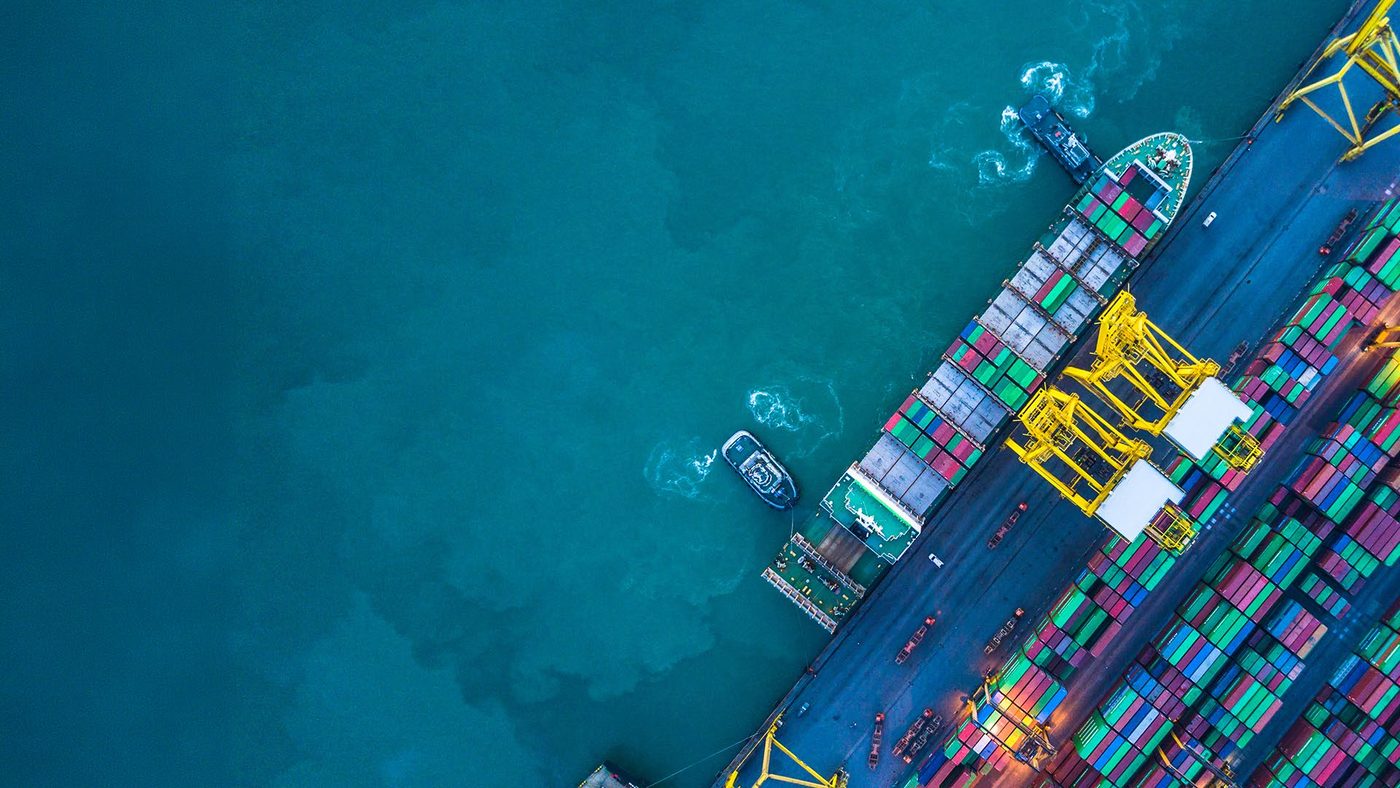 Aerial view of a container ship berthed at a port terminal with tugboats alongside